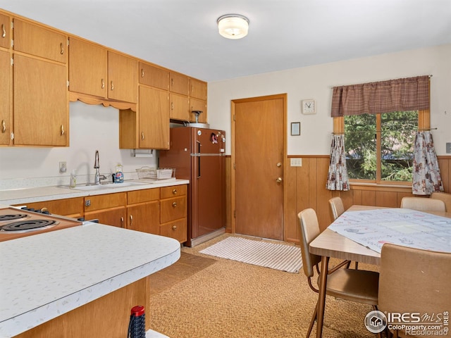 kitchen with wood walls, refrigerator, and sink