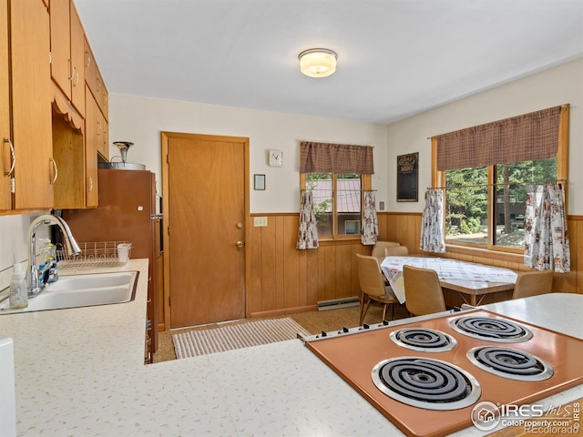 kitchen featuring a baseboard radiator, wood walls, sink, and stove