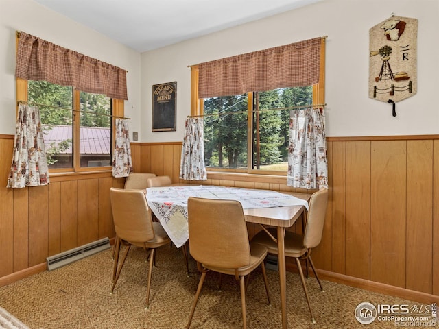 dining room featuring a baseboard heating unit, a healthy amount of sunlight, and wooden walls