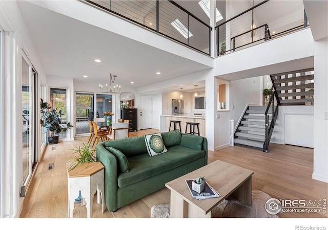 living room featuring a high ceiling, a chandelier, and light wood-type flooring