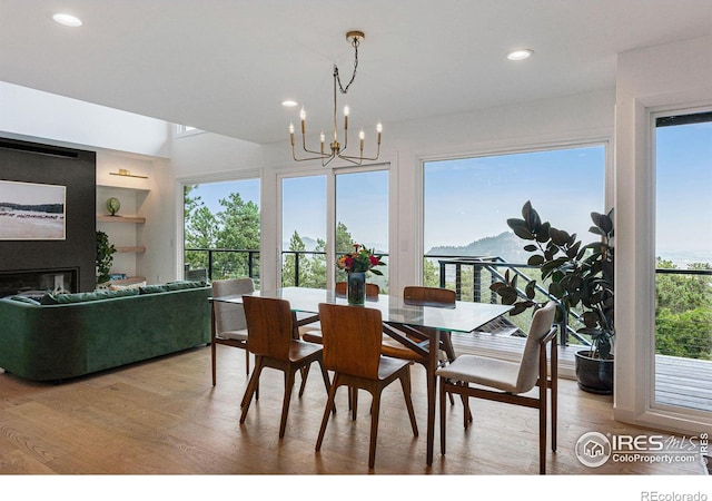 dining space with wood-type flooring, built in features, and a notable chandelier