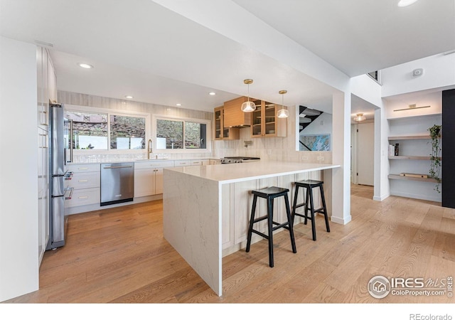 kitchen featuring sink, a kitchen breakfast bar, hanging light fixtures, kitchen peninsula, and stainless steel dishwasher