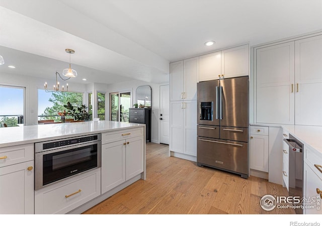 kitchen featuring decorative light fixtures, white cabinets, light hardwood / wood-style floors, and stainless steel appliances