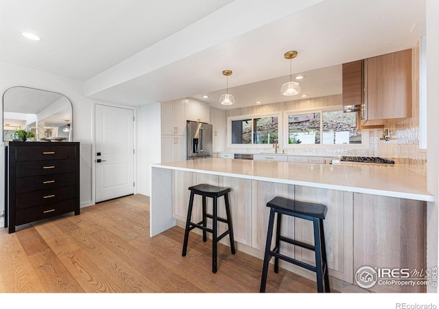 kitchen with kitchen peninsula, backsplash, decorative light fixtures, and stainless steel appliances