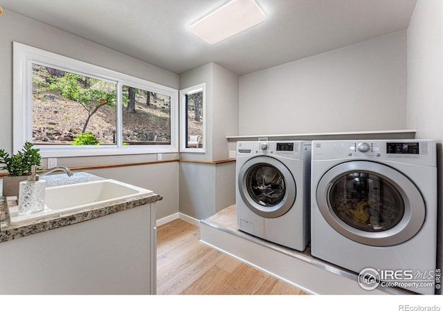 laundry area with sink, light wood-type flooring, and separate washer and dryer