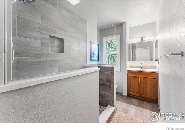 bathroom with vanity and a tile shower