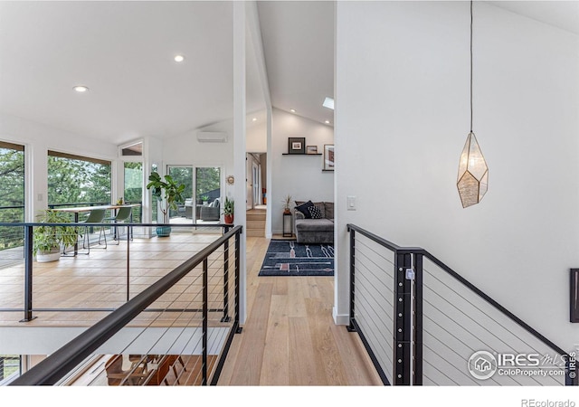 hallway featuring hardwood / wood-style flooring, an AC wall unit, and lofted ceiling