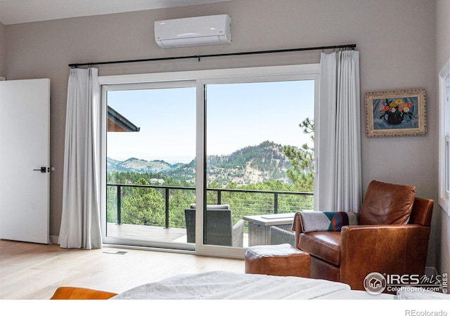 bedroom with a mountain view, hardwood / wood-style flooring, and a wall unit AC