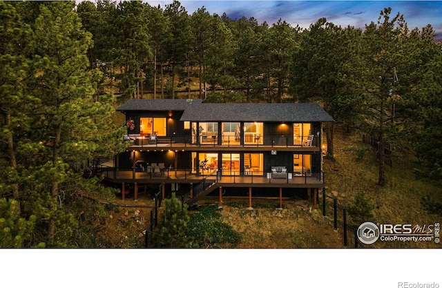 back house at dusk featuring a balcony and a deck