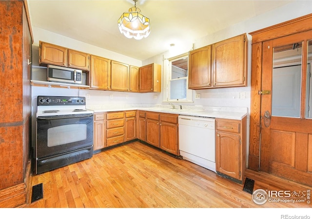 kitchen featuring dishwasher, black range with electric cooktop, light hardwood / wood-style floors, pendant lighting, and sink