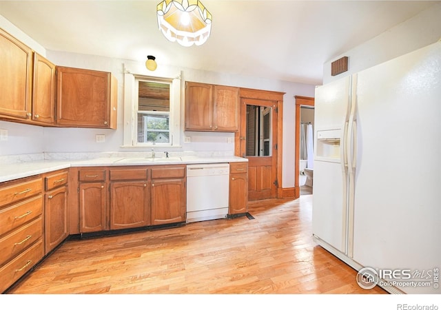 kitchen featuring sink, white appliances, and light wood-type flooring