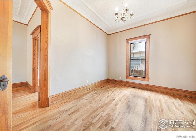 unfurnished room with light wood-type flooring, a chandelier, and crown molding