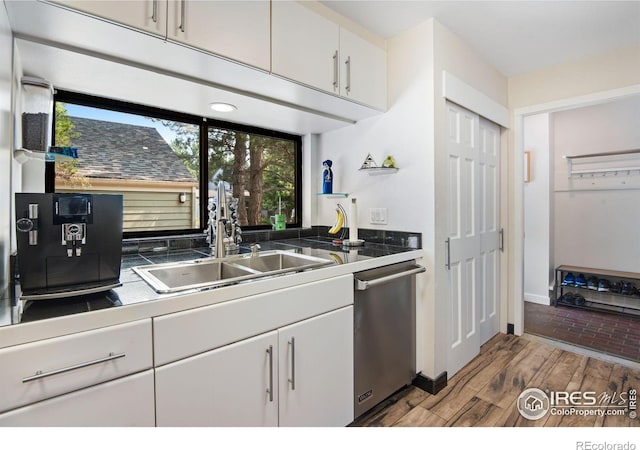 kitchen featuring sink, hardwood / wood-style flooring, white cabinetry, and stainless steel dishwasher