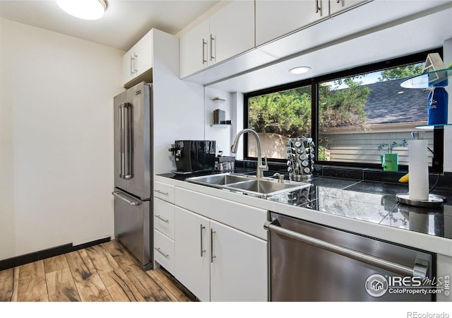 kitchen with sink, stainless steel appliances, white cabinetry, and light hardwood / wood-style floors