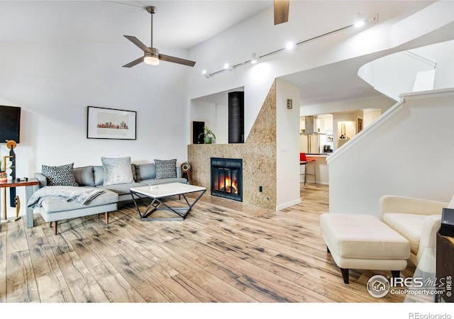 living room featuring light hardwood / wood-style floors, high vaulted ceiling, and ceiling fan