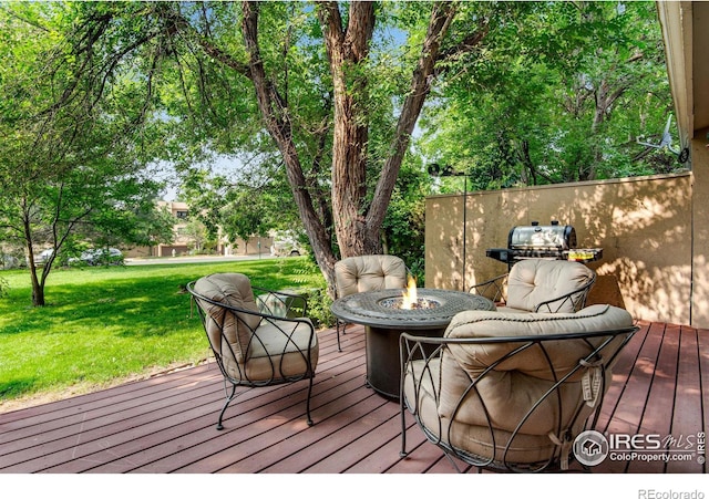 wooden terrace with a fire pit and a lawn