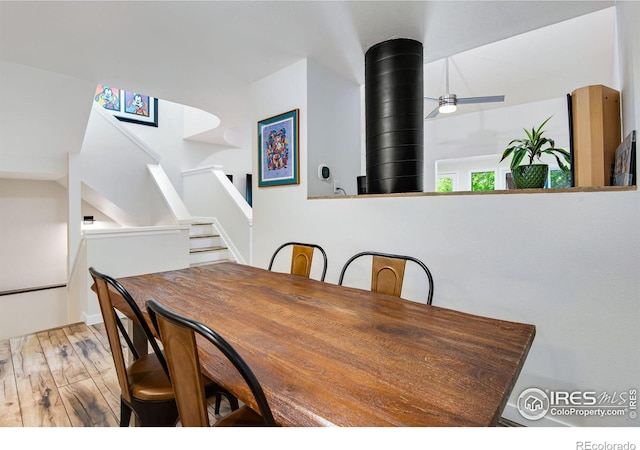 dining room featuring hardwood / wood-style flooring, a wood stove, and ceiling fan