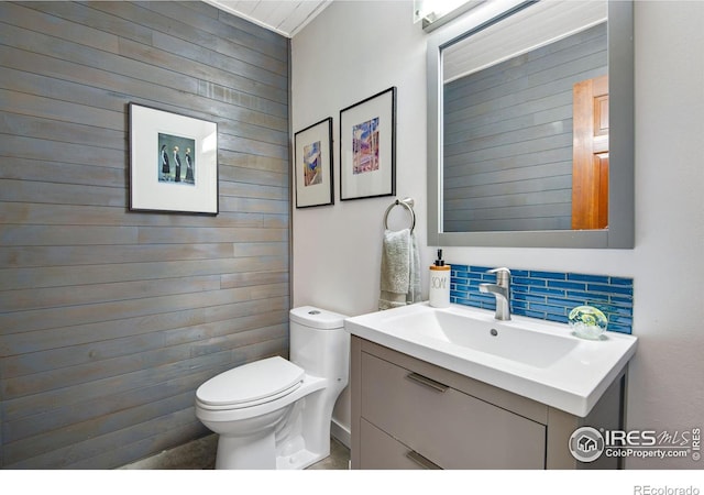 bathroom featuring toilet, vanity, and tasteful backsplash