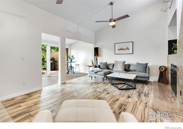 living room with ceiling fan, high vaulted ceiling, light hardwood / wood-style floors, and a fireplace