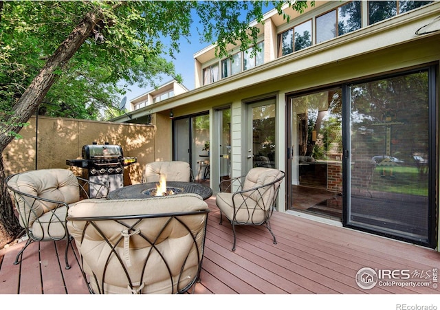 wooden deck with a fire pit and a grill