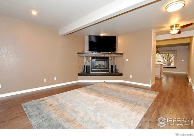 living room with hardwood / wood-style flooring, ceiling fan, and beam ceiling