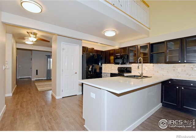 kitchen featuring black appliances, sink, a baseboard heating unit, kitchen peninsula, and light hardwood / wood-style flooring