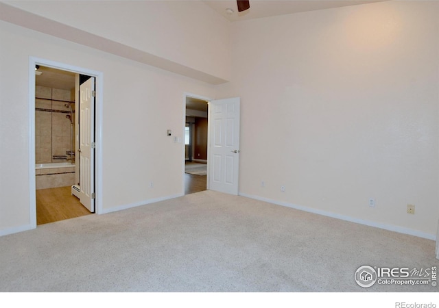 interior space featuring ensuite bath, ceiling fan, light colored carpet, and a walk in closet