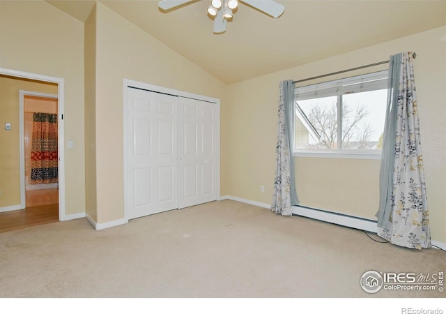 unfurnished bedroom with ceiling fan, carpet flooring, a baseboard radiator, a closet, and vaulted ceiling