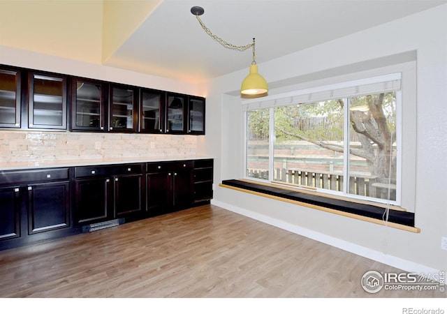 kitchen featuring decorative light fixtures, dark brown cabinets, and light hardwood / wood-style flooring