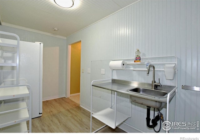 kitchen with white refrigerator, sink, light hardwood / wood-style flooring, and ornamental molding