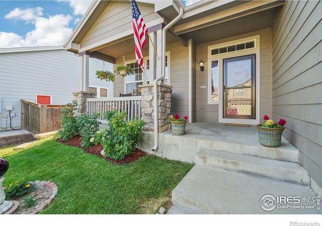 view of exterior entry with a yard and a porch