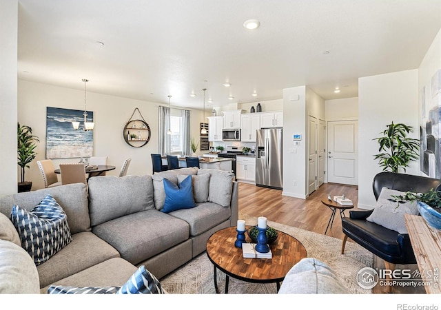 living room with an inviting chandelier and light hardwood / wood-style floors