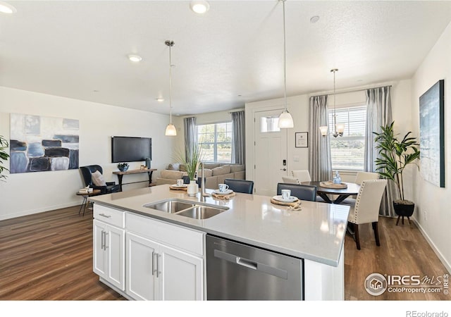 kitchen featuring sink, white cabinetry, hanging light fixtures, stainless steel dishwasher, and an island with sink