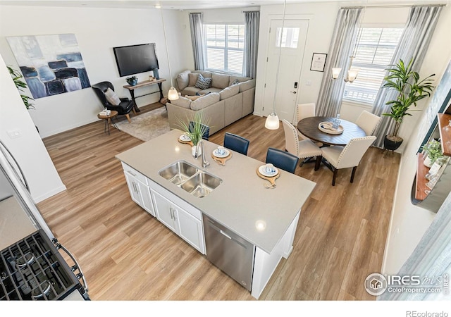 kitchen with stainless steel dishwasher, light hardwood / wood-style floors, a center island with sink, and white cabinets