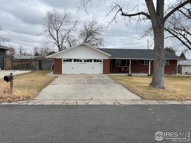 ranch-style house with an attached garage, covered porch, fence, concrete driveway, and a front yard