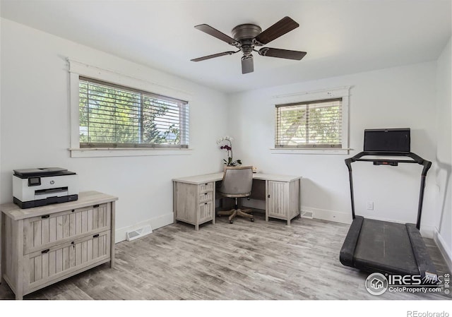 home office featuring light wood finished floors, baseboards, visible vents, and a wealth of natural light