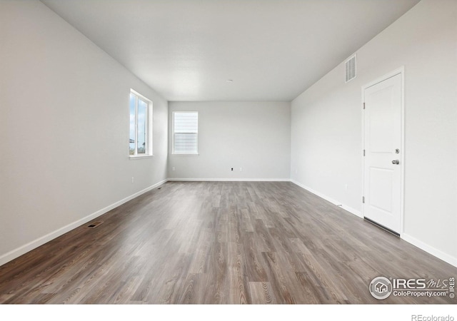 spare room with visible vents, baseboards, and wood finished floors