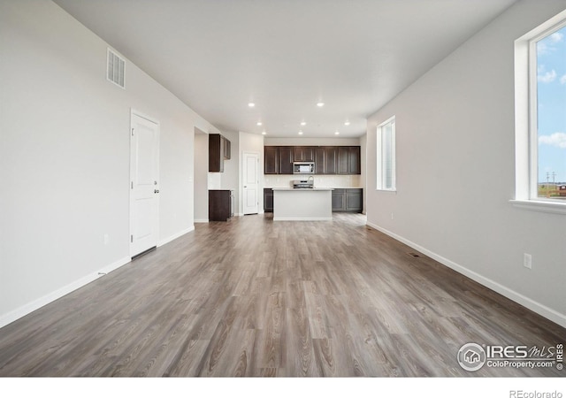 unfurnished living room with baseboards, visible vents, and a healthy amount of sunlight