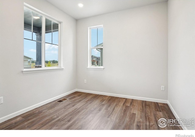 empty room featuring visible vents, baseboards, and wood finished floors