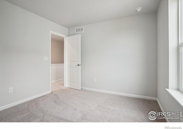 empty room with carpet, visible vents, and baseboards