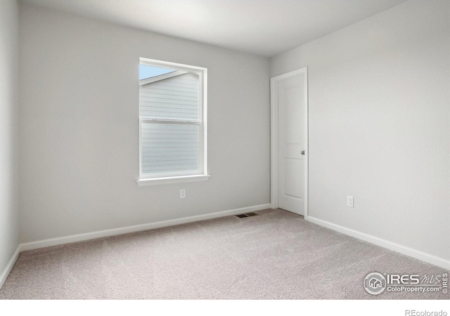 carpeted spare room featuring visible vents and baseboards