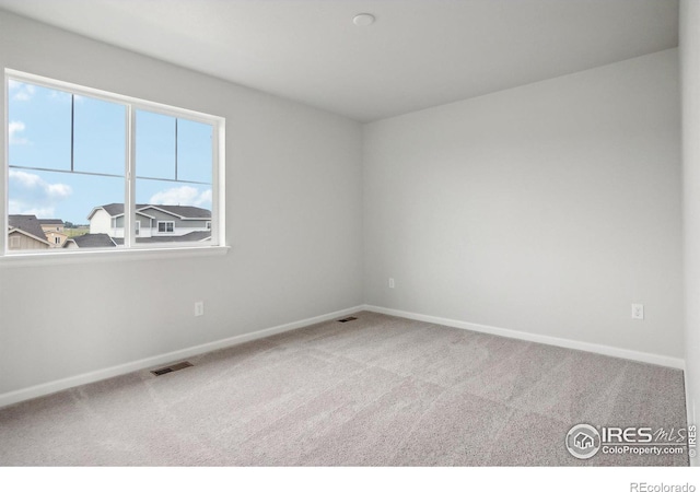 spare room with carpet, visible vents, and baseboards