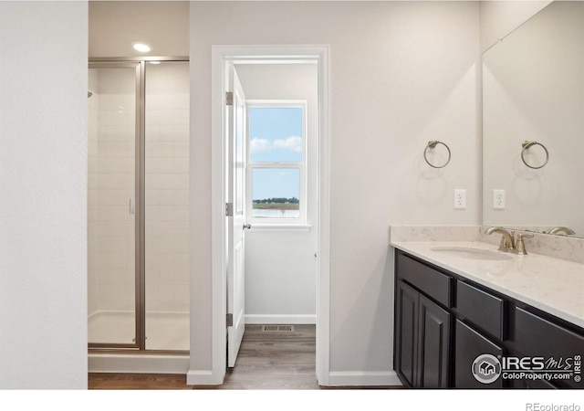 bathroom featuring a stall shower, vanity, baseboards, and wood finished floors