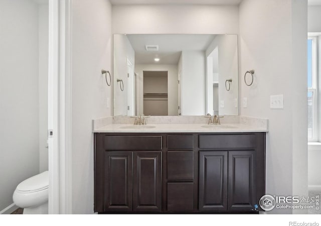 full bathroom with double vanity, a sink, and toilet