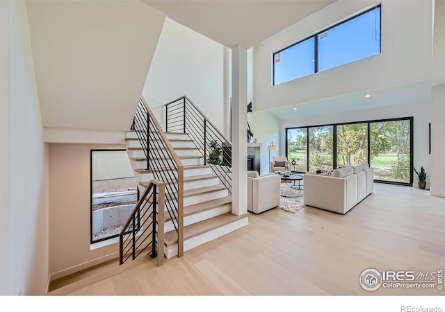 living room with a towering ceiling and light wood-type flooring