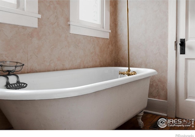 bathroom featuring hardwood / wood-style flooring and a tub to relax in