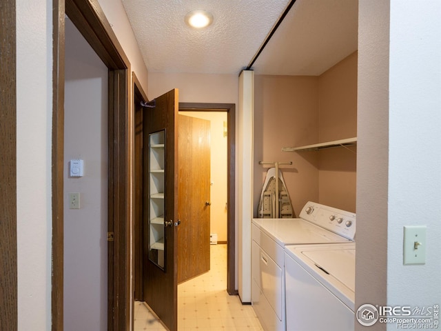 laundry room with laundry area, washer and clothes dryer, light floors, and a textured ceiling