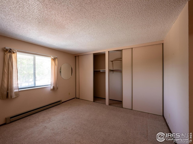 unfurnished bedroom featuring light carpet, baseboard heating, a closet, and a textured ceiling