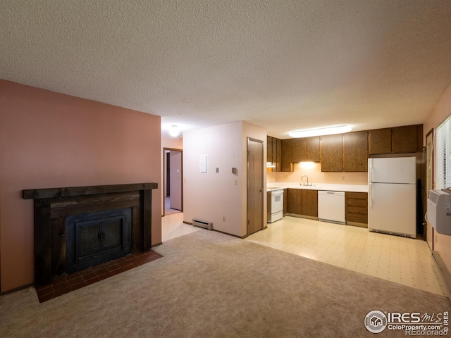 kitchen with white appliances, light colored carpet, a fireplace with flush hearth, light countertops, and a sink