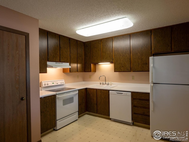 kitchen featuring white appliances, a sink, under cabinet range hood, and light floors